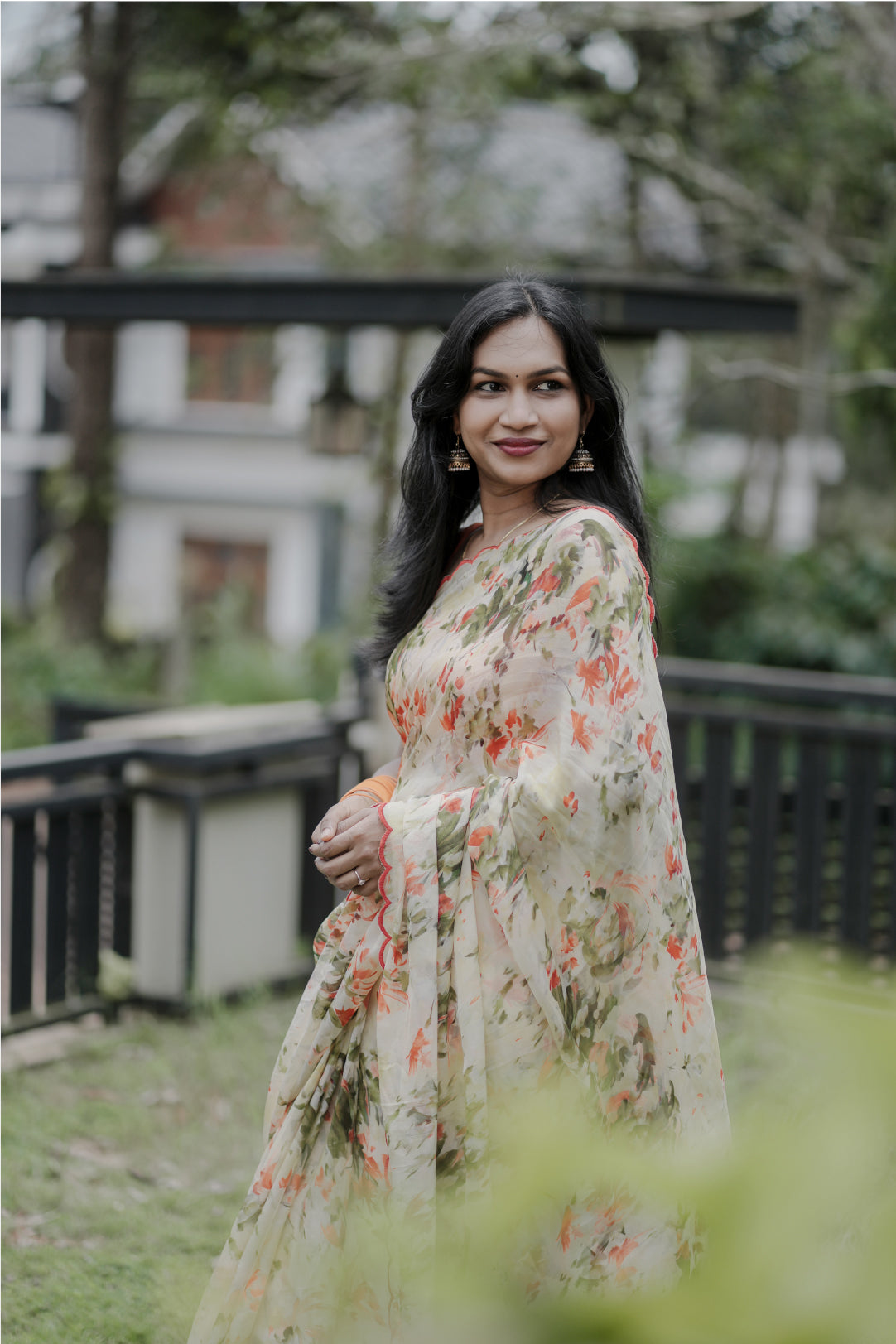 Elaria saree back view showing orange digital floral print on light yellow organza with garden setting