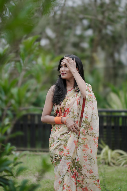Woman in Elaria saree standing outdoors wearing light yellow premium organza with orange digital florals and greenery
